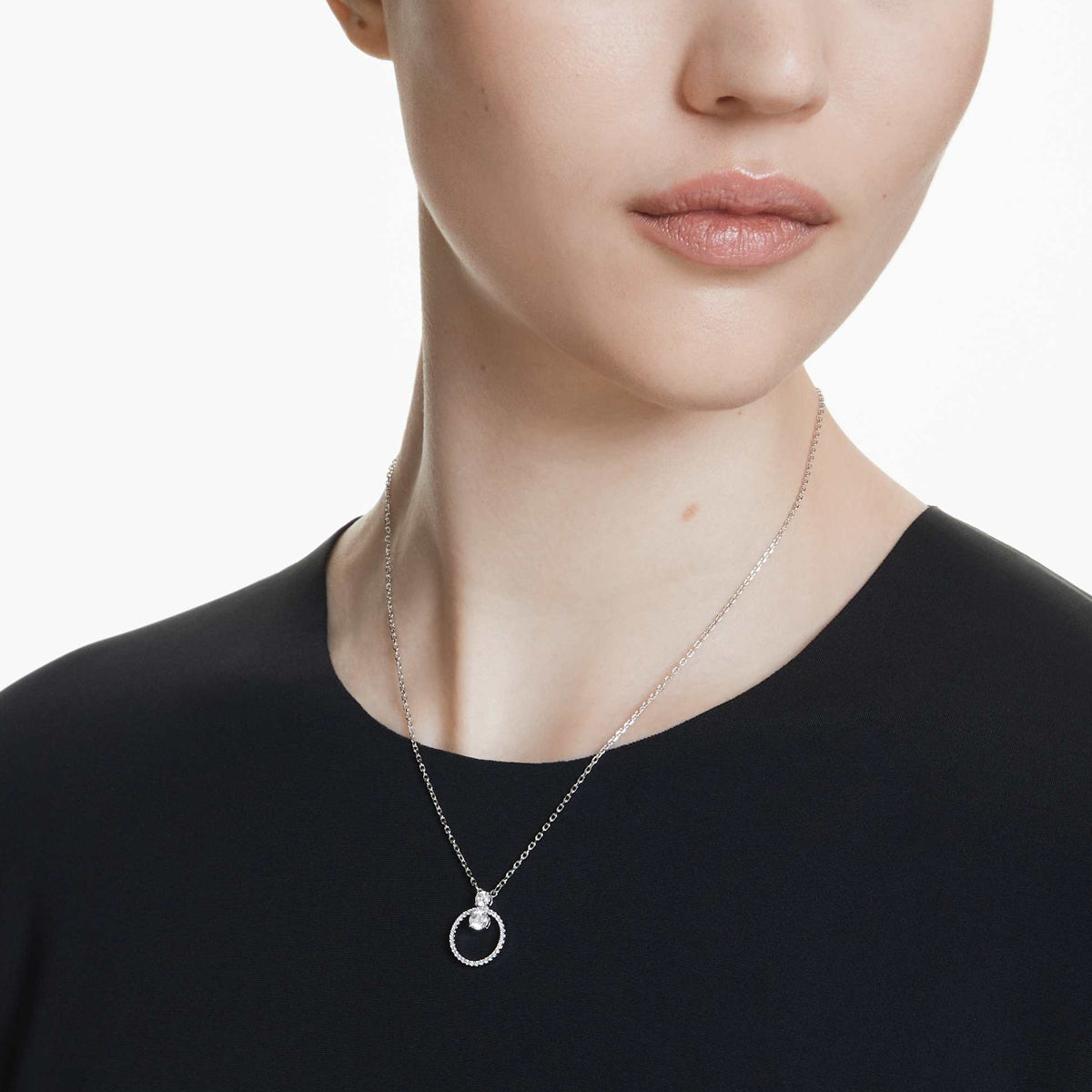 Woman wearing SWAROVSKI Mod. 5692261 silver necklace with round pendant, showcasing elegant jewelry design. Suitable for ladies, quartz analog.