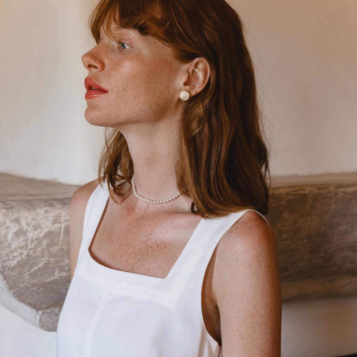 Woman wearing pearl earrings and necklace in white dress