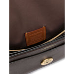 Interior view of Coach Tabby 26 leather shoulder bag with brown pebbled texture and logo plaque, showing zip-fastening pocket.