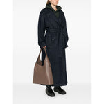 Person wearing a dark coat holding a Coach Brooklyn leather hobo bag in light brown calf leather with logo stamp to the front.