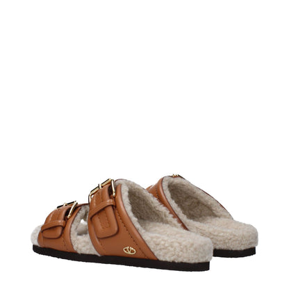Valentino Garavani Brown Leather Slippers with buckle closure and rubber sole, featuring an open toe and casual style.