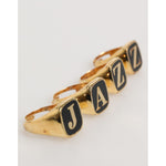 Dolce & Gabbana Gold Tone Brass JAZZ Letter Set 4 Pieces Adjustable Ring displayed with black enamel letters.