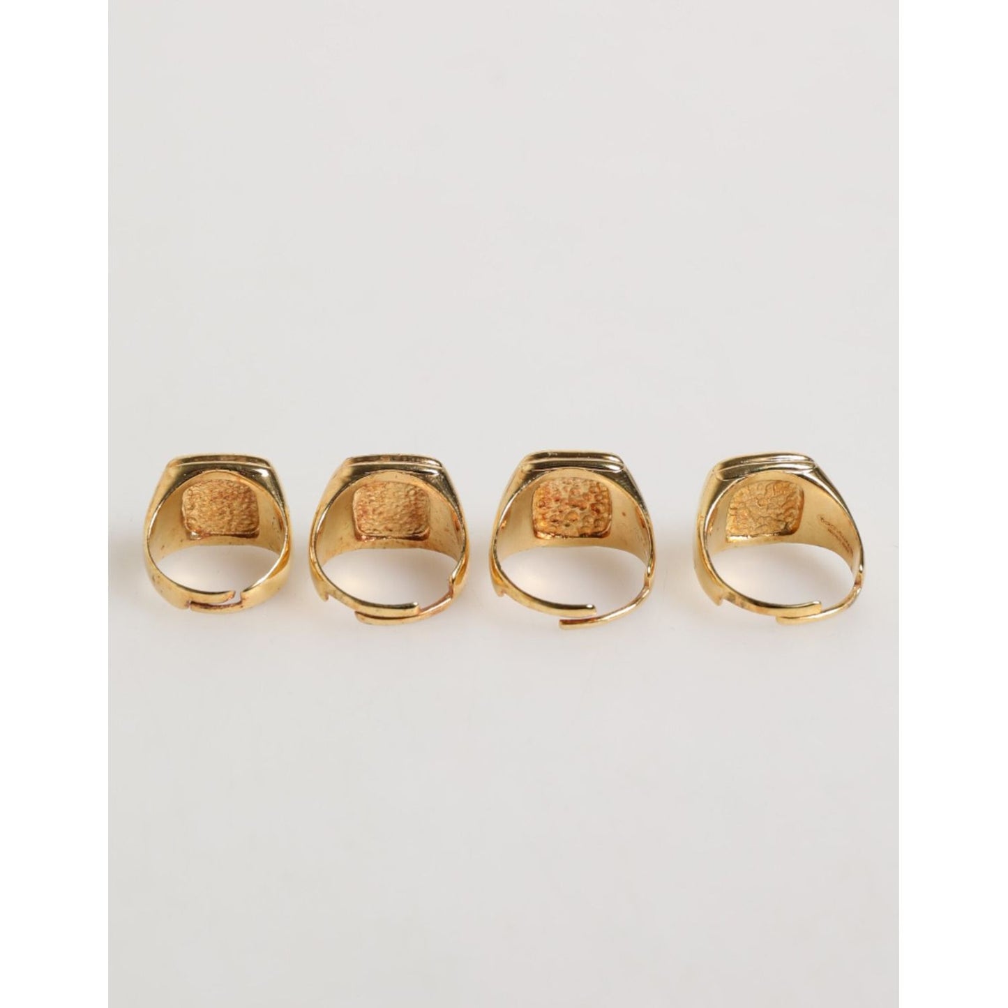 Dolce & Gabbana Gold Tone Brass JAZZ Letter Set 4 Pieces Adjustable Ring displayed in a row, showcasing luxurious gold design.