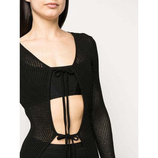 Woman wearing ANDREĀDAMO Andrea Adamo Sweaters Black, semi-sheer knit cardigan with ribbed detailing and front tie fastening.