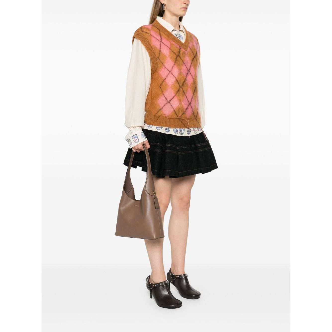 Woman holding Coach Brooklyn leather hobo bag in light brown calf leather, showcasing single shoulder strap and logo details.