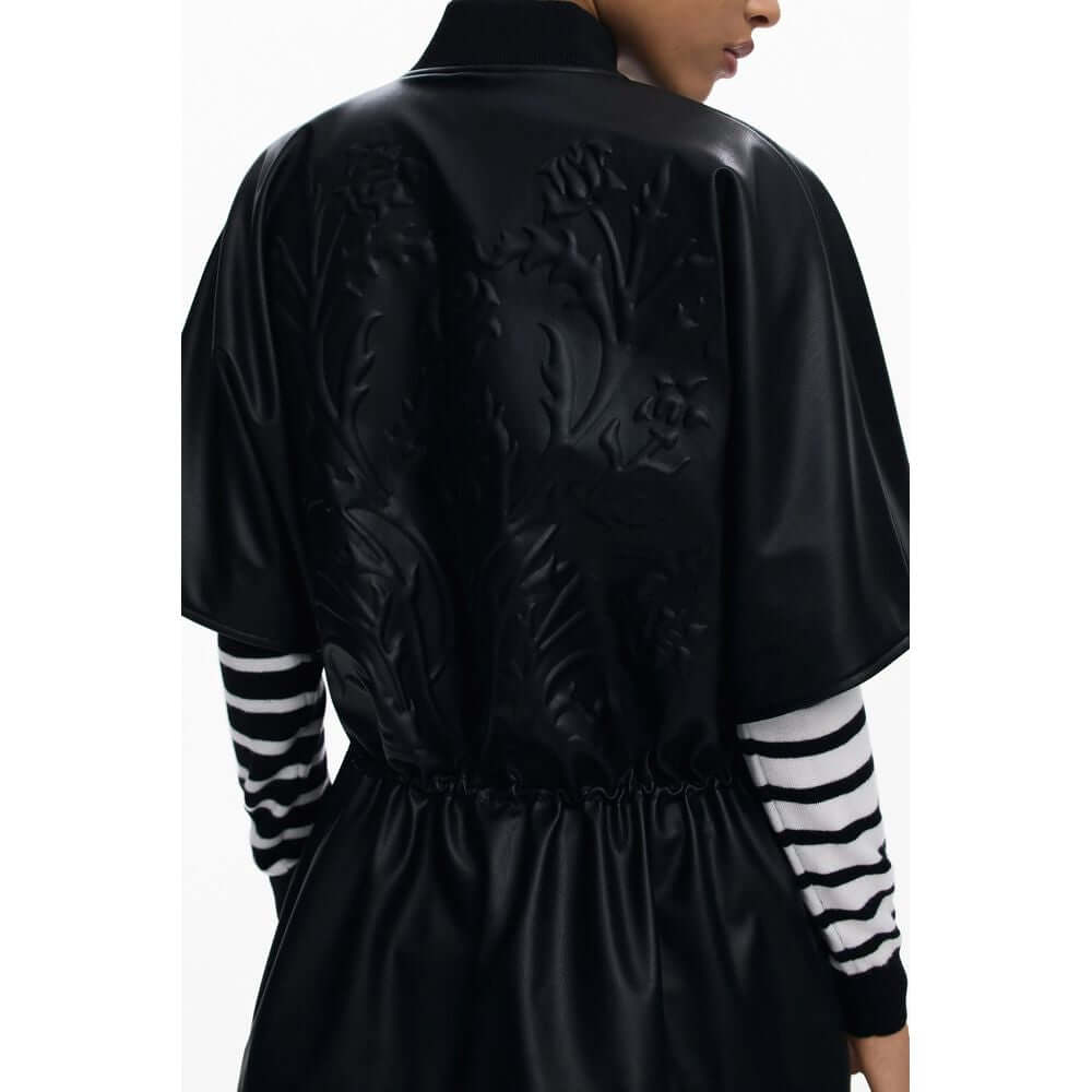 Woman wearing Desigual Black Polyethylene Women Poncho with embossed floral design and drawstring waist, rear view.
