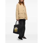 Person holding a Ganni Organic cotton XXL tote bag with black graphic print and logo, featuring two top handles made from organic cotton.
