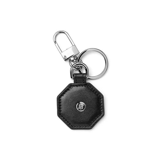 Octagonal black leather keychain with metal accents and a logo, featuring a key ring and clip.
