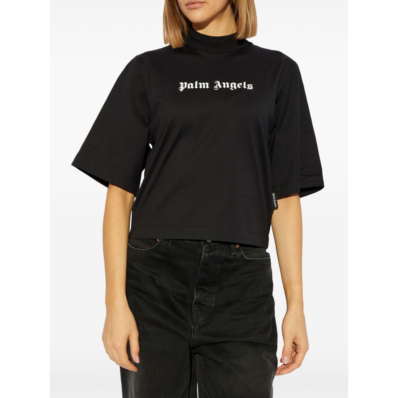 Woman wearing Palm Angels crop T-shirt with logo, black crew neck, drop shoulders, short sleeves, straight hem, size S, standing view.