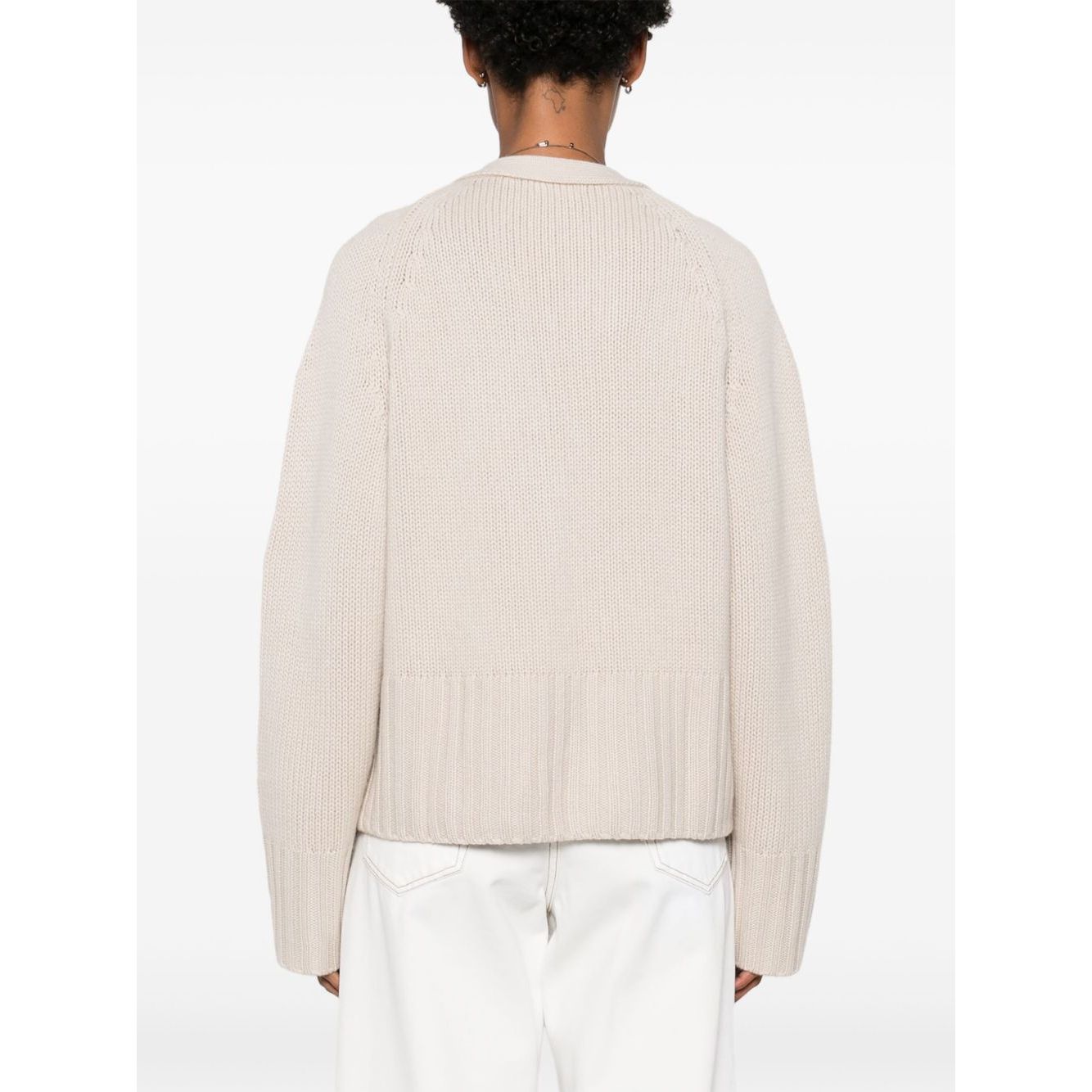 Back view of a SOFT GOAT Sweaters Ivory cashmere cardigan with ribbed trim and plunging V-neck, showcasing its light beige color and design details.