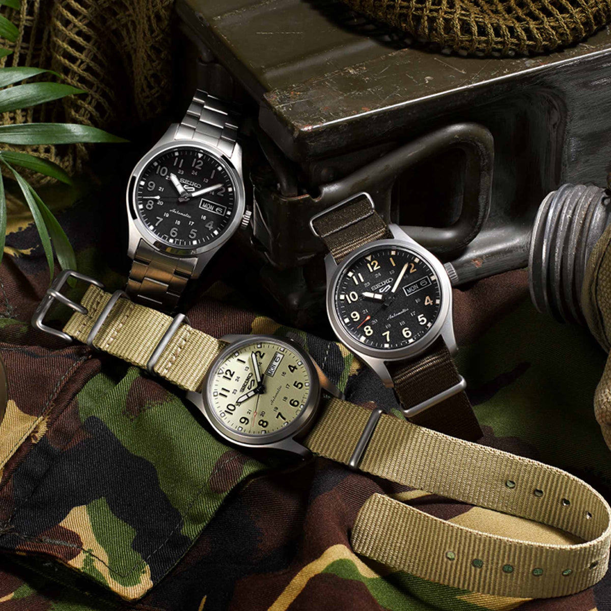 Collection of SEIKO MOD. SRPJ85K1 wristwatches with fabric straps and stainless steel cases displayed on camo fabric.