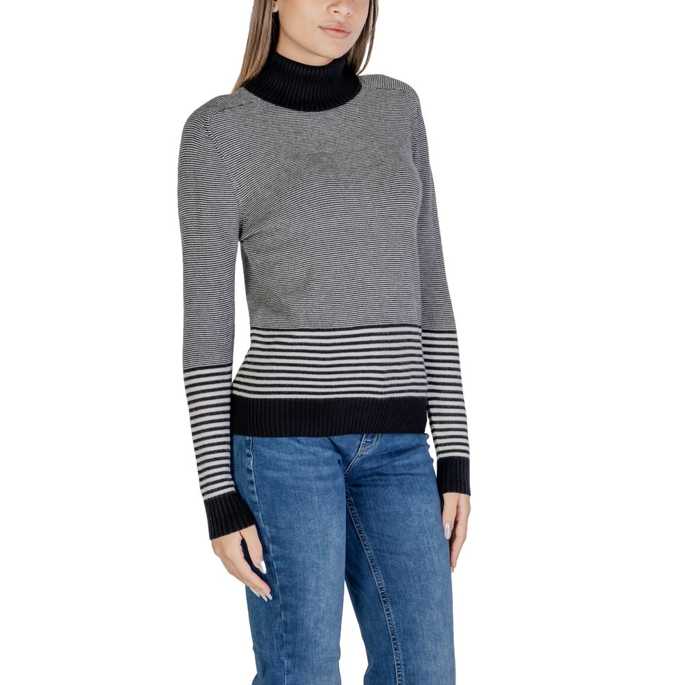Woman wearing Sandro Ferrone Black And White Viscose Turtleneck with striped pattern and jeans