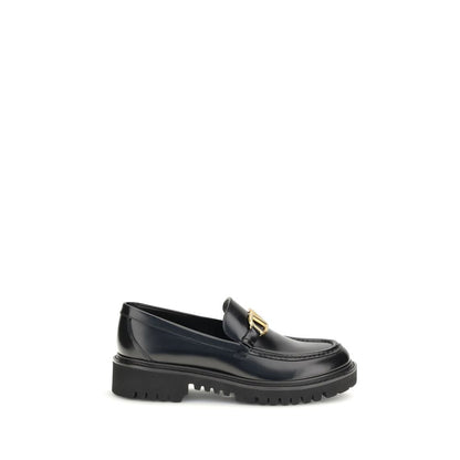 Valentino Garavani Black Leather Slip-On Loafers with brass VLogo detail on a rubber lug sole, side view.