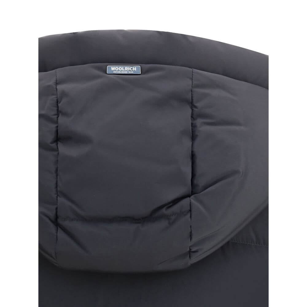 Close-up view of the Woolrich Black Goose Down Coat hood, showcasing padded quilting and a logo patch, ideal for warmth in AW25.